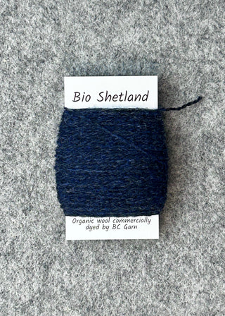 Navy blue yarn swatch with 'Bio Shetland' label on a gray textured background