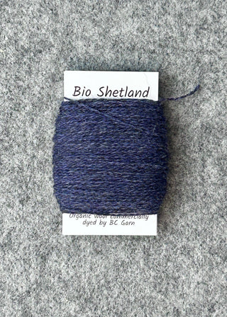 Blue yarn bobbin with a label on a textured gray background