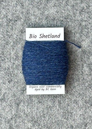 Blue yarn sample with a label on a gray textured background