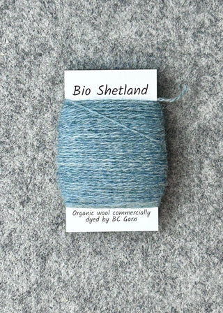 Blue bobbin of yarn with a label on a gray textured background